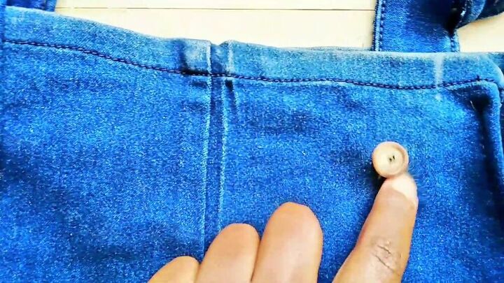 how to easily make a dungaree dress from old jeans, Hand sewing buttons onto the dungaree dress