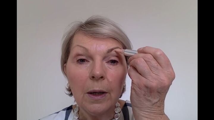 how to easily perfectly apply eye makeup for mature women, Applying highlighter just below the eyebrow