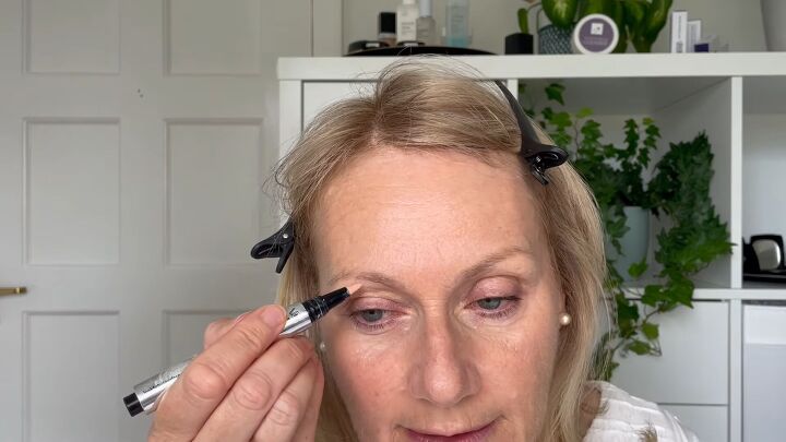 quick easy 5 minute makeup routine for women over 50, Applying highlighter under the eyebrows