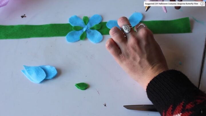how to easily make a colorful diy trolls costume for kids or adults, Gluing the blue petals onto the green strips