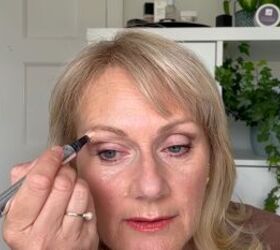 this warm autumn eye makeup for older eyes is perfect for fall, Applying highlighter underneath the brow