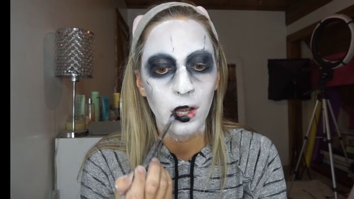 how to do super spooky makeup for a terrifying valak the nun costume, Applying black paint to the lipsticks