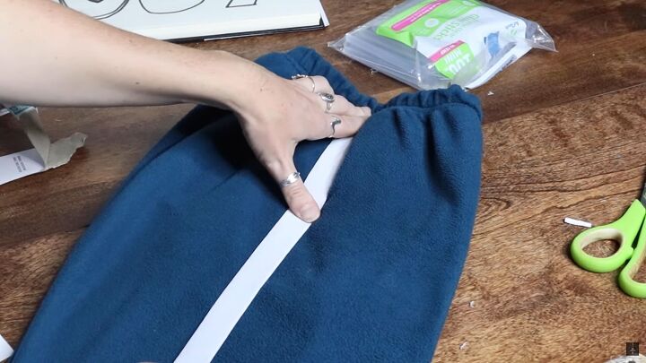 how to make a diy squid game costume easy player tracksuit tutorial, Gluing white strips onto the tracksuit pants