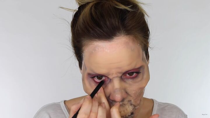 looking for a fun halloween look try this chilling zombie sfx makeup, Applying a red makeup pencil to the waterline