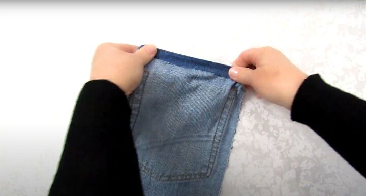 how to make a jean pocket purse with cute fringe detailing, Folding the top of the bag over