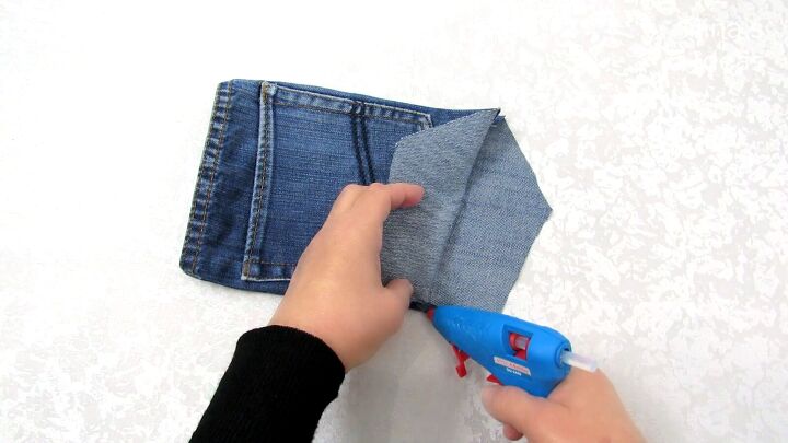 how to make a jean pocket purse with cute fringe detailing, Gluing the bottom of the DIY denim purse