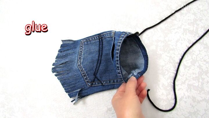 how to make a jean pocket purse with cute fringe detailing, Gluing the cord strap to the DIY purse from old jeans
