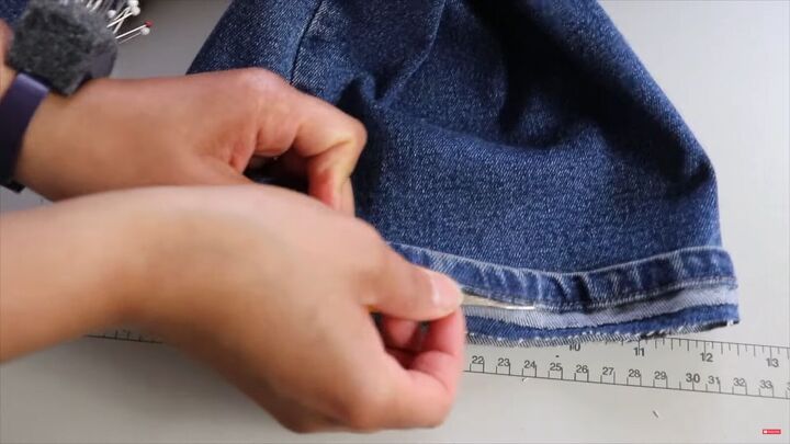 jeans too long here s how to hem flared jeans keep the original hem, Using a seam ripper to remove the stitching