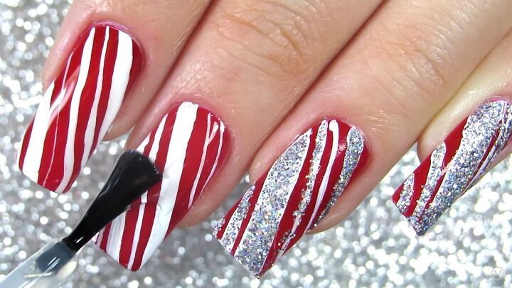 how to do cute red white candy cane christmas nails for the holidays, Applying a clear top coat to the nail art