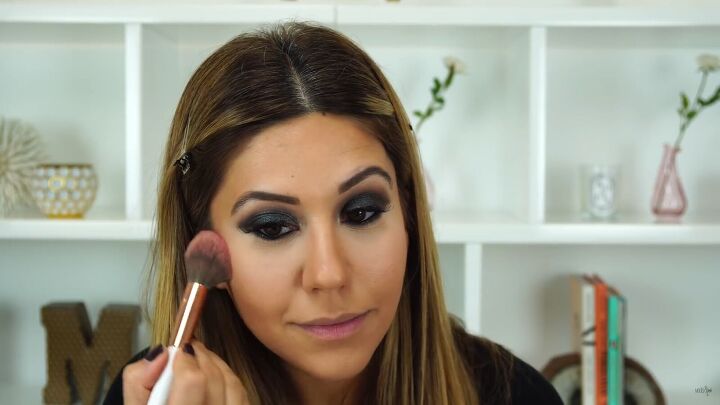 this sexy black glitter makeup look is perfect for holiday parties, Applying blush to the tops of cheekbones