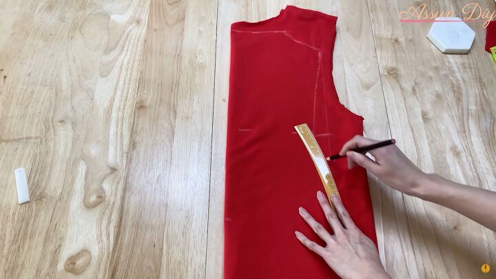 how to make a cute diy christmas dress out of an old red hoodie, Using a curved ruler to mark the hips