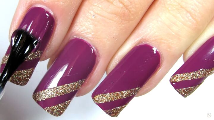 these simple gold purple christmas nails are like berries cream, Applying a clear top coat to the purple nails