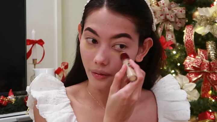 need some festive makeup inspo try this easy holiday makeup look, Applying concealer under the eyes