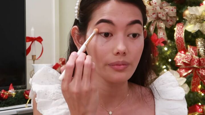 need some festive makeup inspo try this easy holiday makeup look, Applying a light orange eyeshadow color