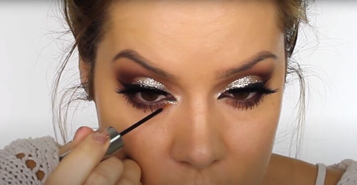 this dark sultry festive makeup look is perfect for a holiday party, Applying glitter to the inner corner