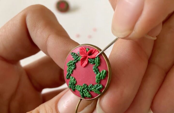 these intricate diy poinsettia earrings are made from polymer clay, Placing the red poinsettia on the earrings