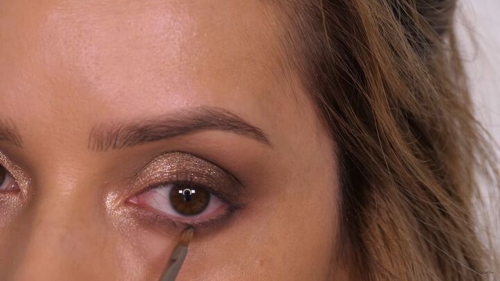 how to do a glamorous bronze makeup look with swarovski crystals, Lining the lower lashes with eyeshadow