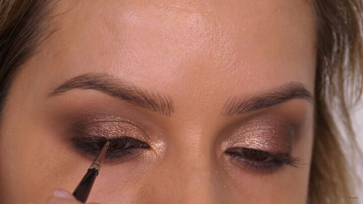 how to do a glamorous bronze makeup look with swarovski crystals, Smudging eyeliner across the lash line