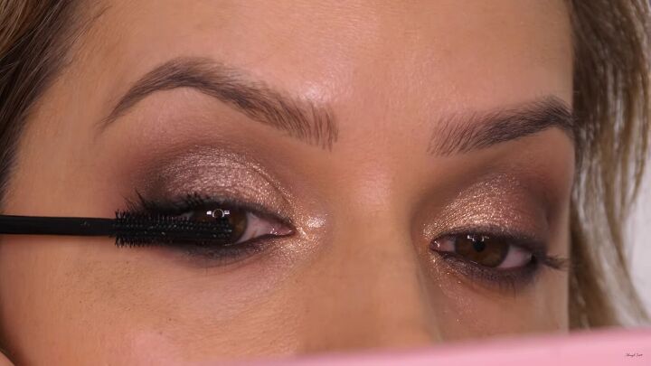 how to do a glamorous bronze makeup look with swarovski crystals, Applying mascara to eyelashes