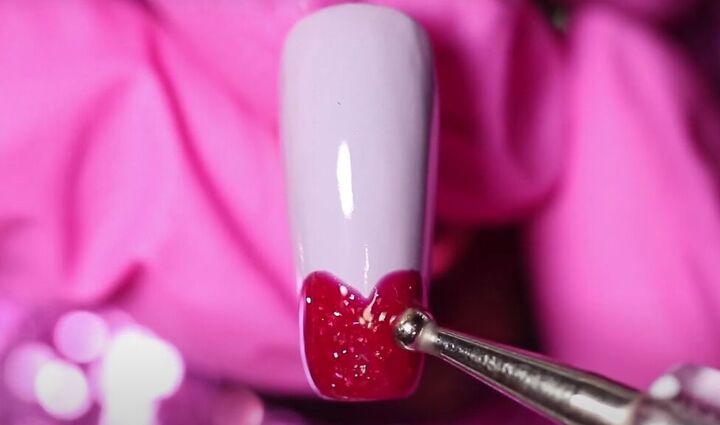 how to do adorable red purple and pink valentine s day nails, Painting a glittery heart on the nail tip