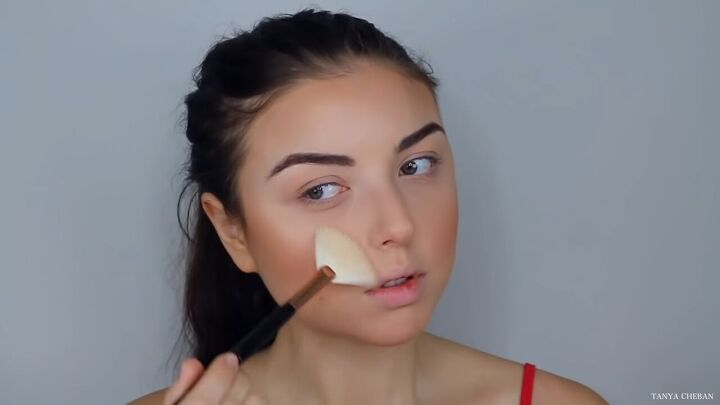 how to do effortlessly sexy red valentine s day makeup, Applying highlight with a fan brush