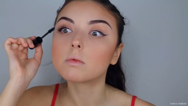 how to do effortlessly sexy red valentine s day makeup, Applying mascara to the upper lashes
