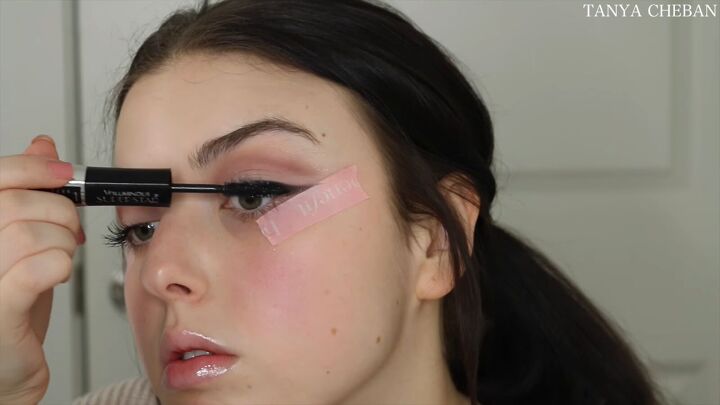 how to do simple valentines day makeup for a soft feminine vibe, Applying mascara to the top lashes