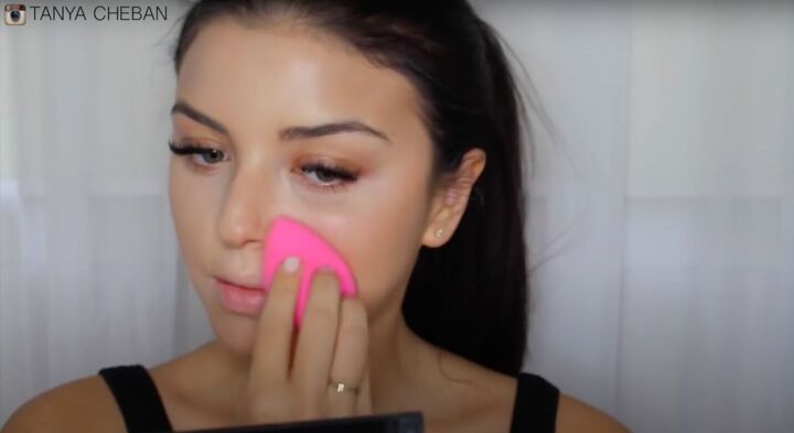 simple contouring highlighting baking routine for a natural glam, Using a beauty blender to pick up excess makeup