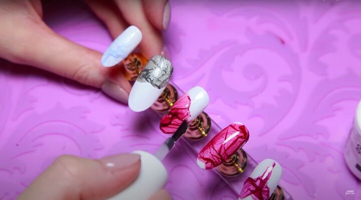 how to create delicate flower petal nail art with water nail polish, Applying a top coat over the flower petal nail art