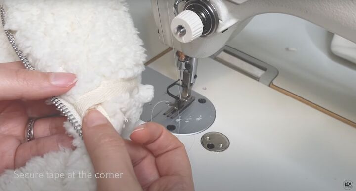 how to sew a sweater with a cute cropped hem half zipper, Securing the tape at the corner of the zipper