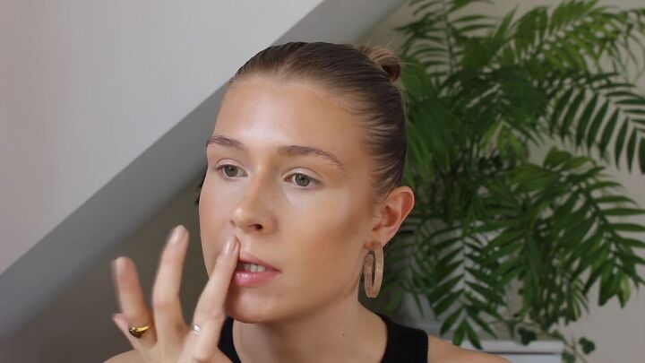 how to create a glowy bronze makeup look for spring summer, Applying highlighter to the cupid s bow