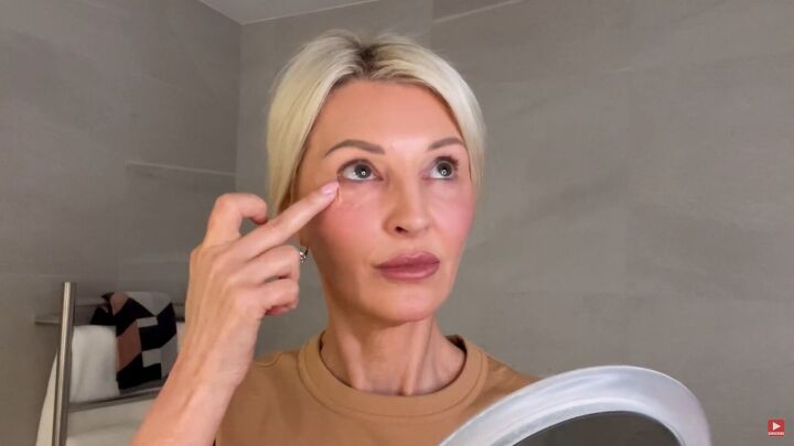 how to hide dark circles under eyes 8 key tips for women over 50, Applying color corrector under the eyes with fingers
