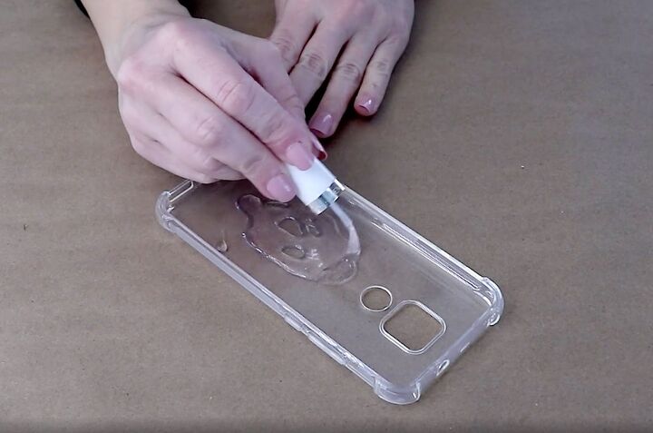 how to easily make a pretty pressed flower phone case for spring, Spreading the clear nail polish with the brush