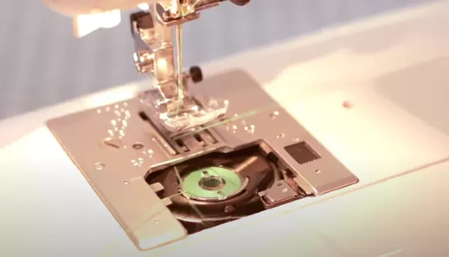 how to replace a sewing machine needle in under 5 minutes, up close shot of sewing machine needle and feed plate