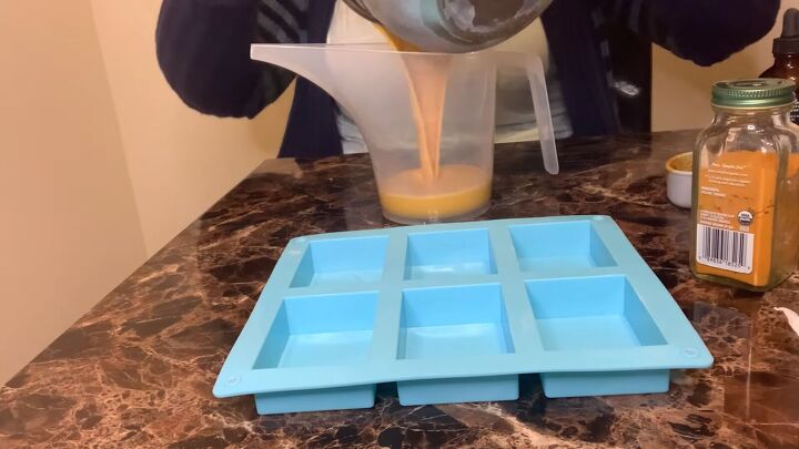 how to make a melt pour turmeric honey soap recipe, Pouring the turmeric and honey soap into a jug