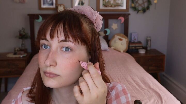 how to do a cute cottagecore makeup look in 7 simple steps, Using a freckle pen to draw on freckles