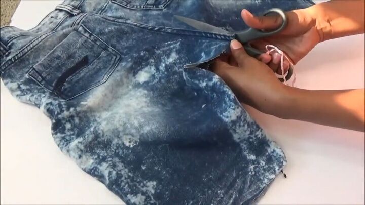how to quickly turn your old distressed jeans into a stylish skirt, Cutting up the center of the jeans on the back