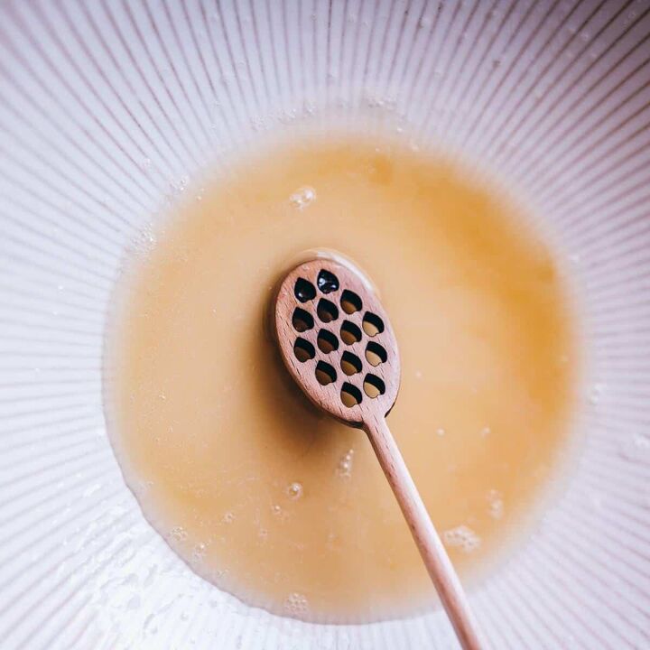diy homemade honey bubble bath recipe, a wooden honey spoon swirling honey bubble bath recipe