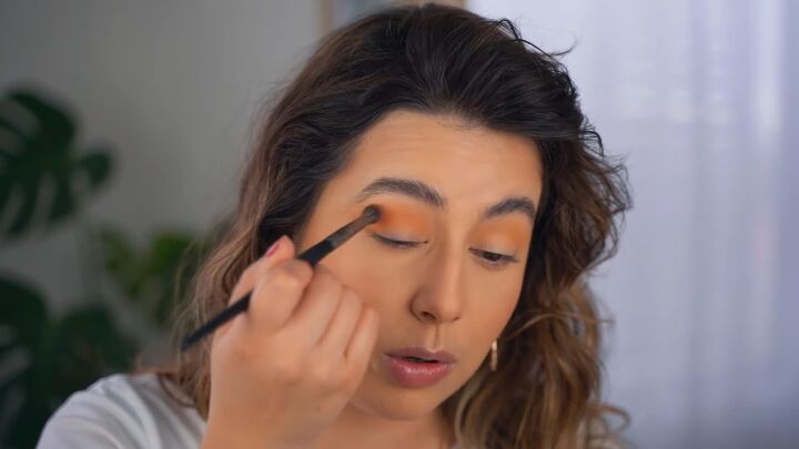 how to create a glam orange eye makeup look, Applying orange eyeshadow