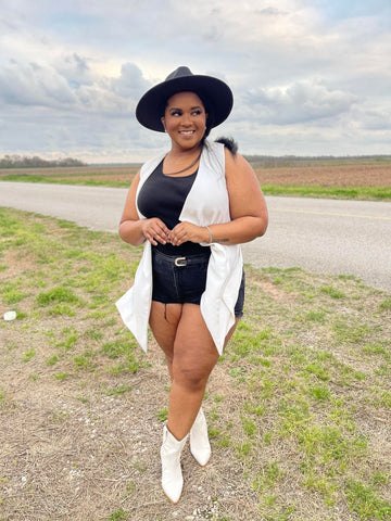 1 accessory you need for the houston rodeo morgan b styles, Morgan B Styles is standing in a dirt road wearing black gold chain fedora hat black top black ripped shorts white vest and white cowboy boots