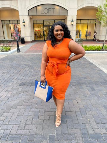 spring 2023 color we are loving morgan b styles, Morgan B wearing a sleeveless orange tie around the waist dress with a color block nude and blue purse