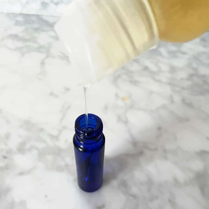 Pouring almond oil into a blue bottle to make homemade perfume oil