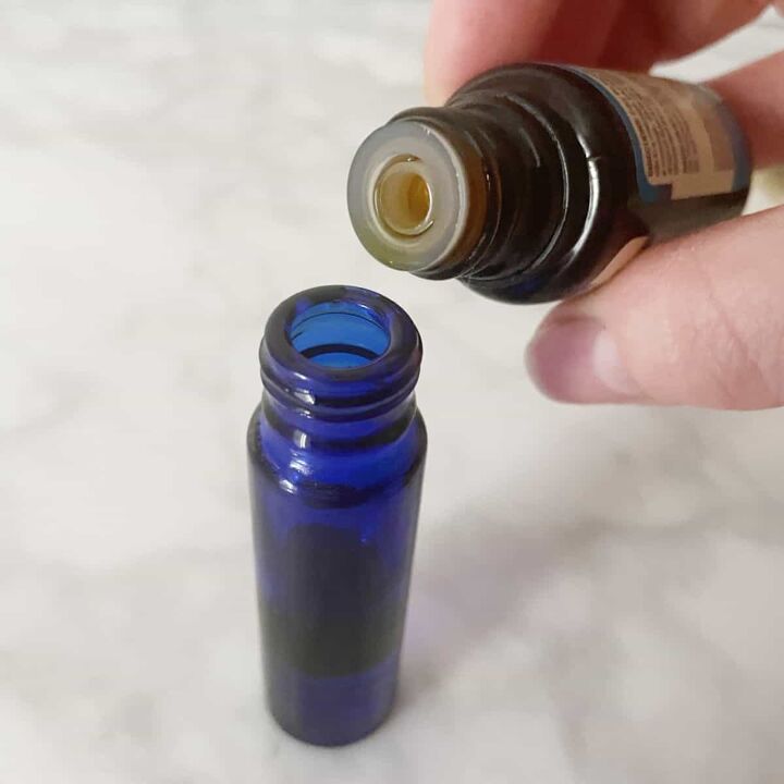 Adding essential oils to homemade perfume oil in a blue bottle