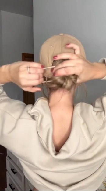 how to wear a cute low bun hairstyle with hat, Adding hair tie