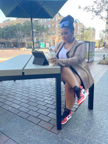 the blazer you did not know you needed, Morgan B working on her IPad wearing a gold metallic blazer and red white and black Jordan One sneakers