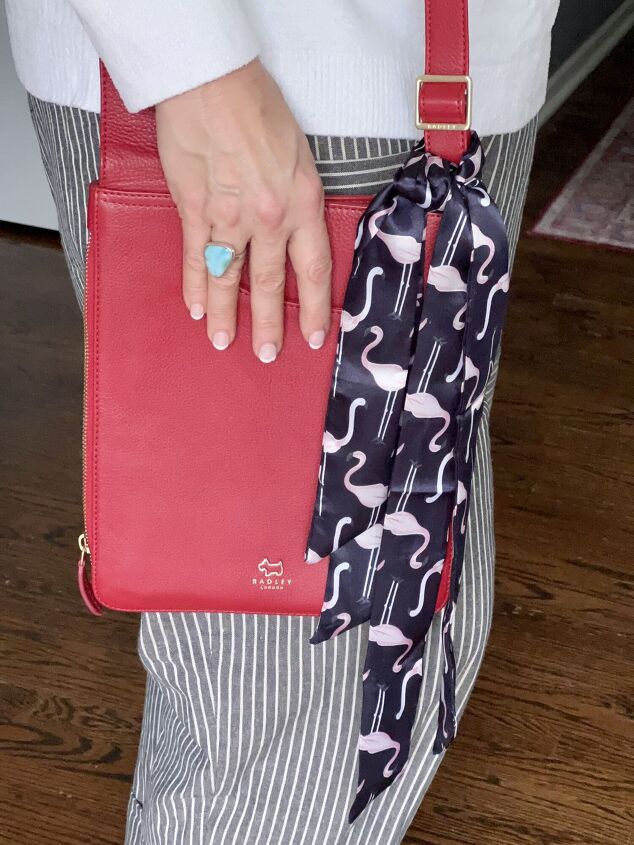 how to tie and style a scarf on your handbag or purse, A red crossbody bag with a flamingo patterned twilly scarf